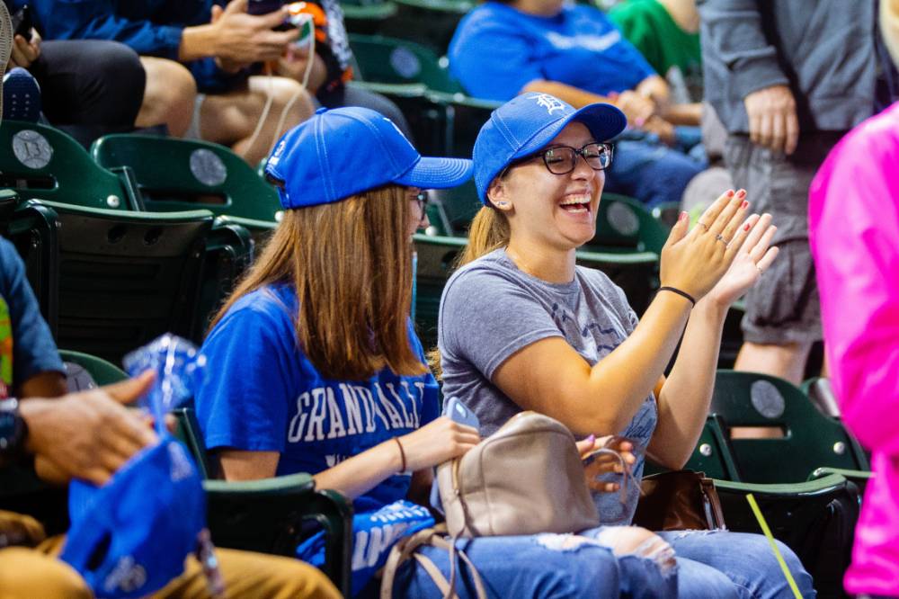 Two women cheering in the stands of Comerica Park with GVSU clothes on